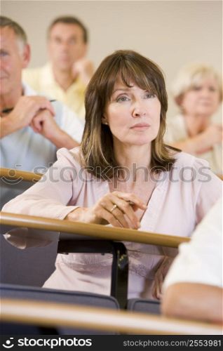 Woman sitting in adult classroom with students in background (selective focus)