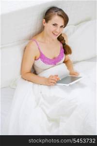 Woman sitting in bed and using tablet pc
