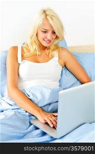 Woman sitting in bed with laptop computer