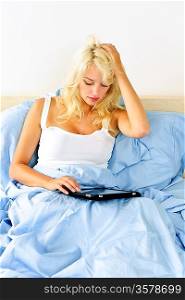 Woman sitting in bed with tablet device