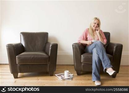 Woman sitting in chair with magazine on cellular phone smiling