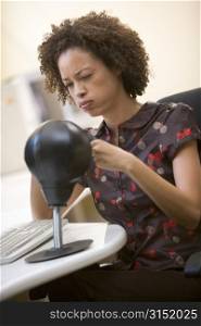 Woman sitting in computer room punching a small punching bag