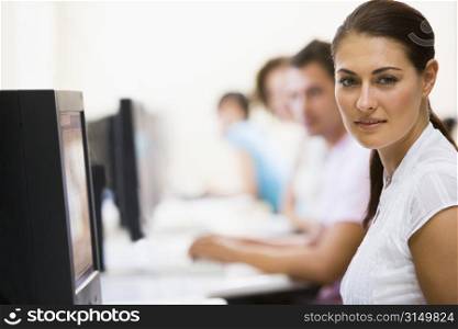 Woman sitting in computer room with people in background