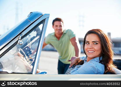 Woman sitting in convertible car, man standing beside car