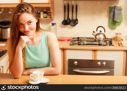 Woman sitting in kitchen with cup of coffee. Young girl and hot energizing beverage that keeps her awake. Energy and caffeine. . Woman with hot coffee beverage. Caffeine.