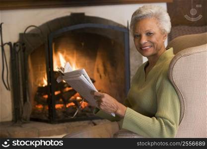 Woman sitting in living room by fireplace with newspaper smiling