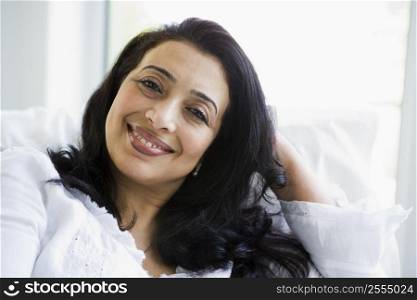 Woman sitting in living room smiling (high key)