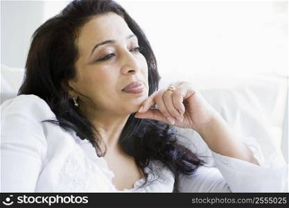 Woman sitting in living room thinking (high key)