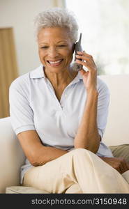 Woman sitting in living room using telephone and smiling