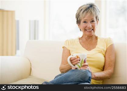 Woman sitting in living room with coffee smiling