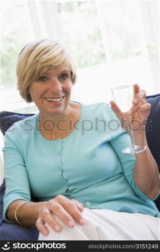 Woman sitting in living room with drink smiling