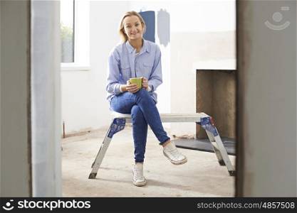 Woman Sitting In Property Being Rennovated