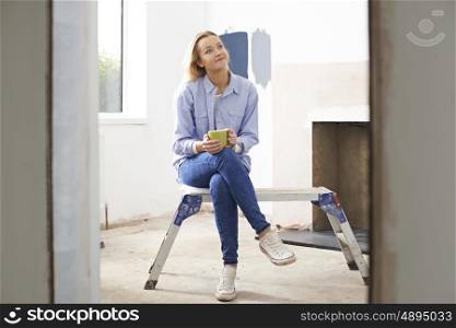 Woman Sitting In Property Being Renovated