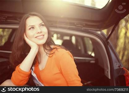 woman sitting in the trunk of the car of a young beautiful spring