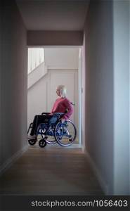 Woman Sitting In Wheelchair At Home In Hallway