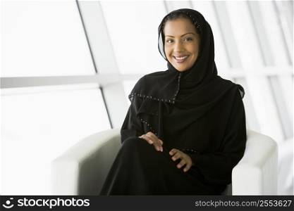 Woman sitting indoors smiling (high key/selective focus)
