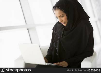 Woman sitting indoors with laptop (high key/selective focus)