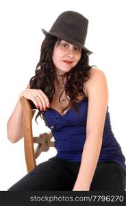 Woman sitting on a chair in a blue top and with long curly black hair anda gray hat, for white background.