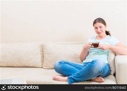 woman sitting on a couch and holding a cup of hot tea