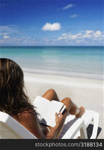 Woman sitting on a lounge chair and reading a book on the beach, Providencia, Providencia y Santa Catalina, San Andres y Providencia Department, Colombia