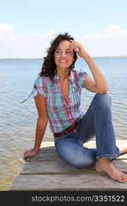 Woman sitting on a pontoon by a lake in summer