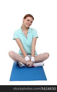 Woman sitting on an exercise mat
