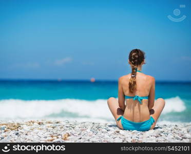 Woman sitting on beach. Rear view