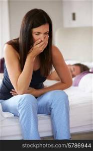 Woman Sitting On Bed And Feeling Unwell