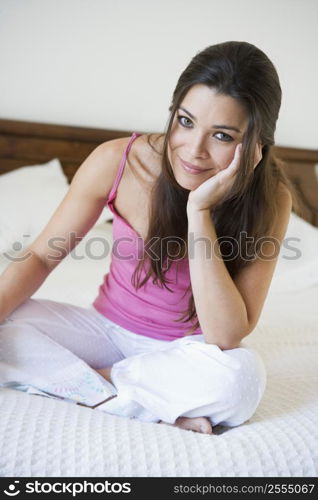 Woman sitting on bed in bedroom smiling (selective focus)