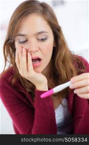 woman sitting on bed looking at pregnancy test