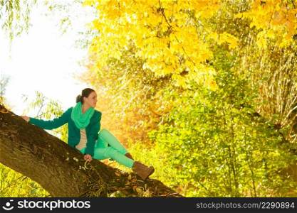Woman sitting on big tree trunk being close to nature, relaxing in woods or park druing autumn weather. Woman sitting on big tree trunk