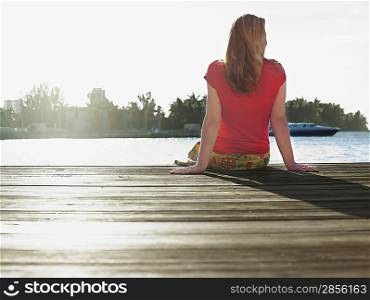 Woman sitting on edge of jetty back view
