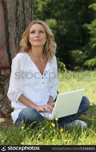 Woman sitting on grass with a computer