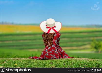 Woman sitting on green grass in green tea field.