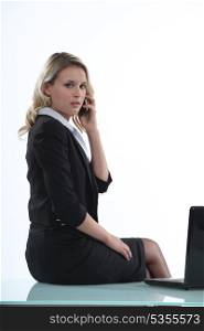 Woman sitting on her desk with a cellphone