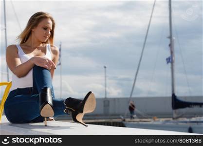 Woman sitting on marina. Resting and relaxation. Young beauty woman relaxing on marina on fresh air. Fashionable blondie girl spending time outdoor.