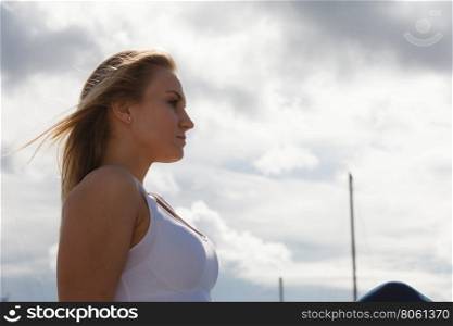 Woman sitting on marina. Resting and relaxation. Young beauty woman relaxing on marina on fresh air. Fashionable blondie girl spending time outdoor.