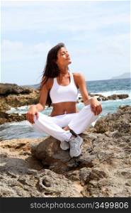 Woman sitting on rocks in fitness outfit