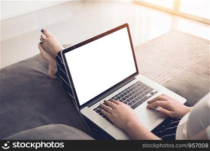 Woman sitting on safa and using laptop blank screen at home.