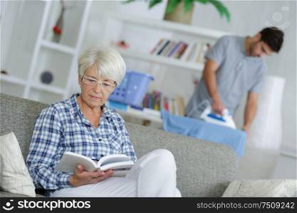 woman sitting on sofa with book while male carer standing