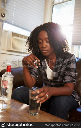 Woman Sitting On Sofa With Bottle Of Vodka And Cigarettes