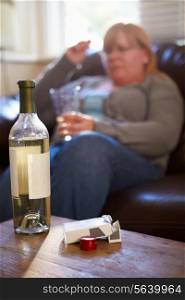 Woman Sitting On Sofa With Bottle Of Wine And Cigarettes