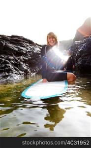 Woman sitting on surfboard in the water