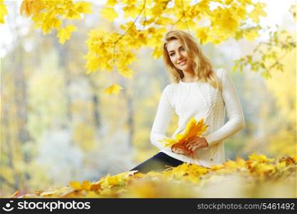 Woman sitting on the autumn leaves in park