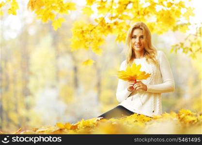 Woman sitting on the autumn leaves in park