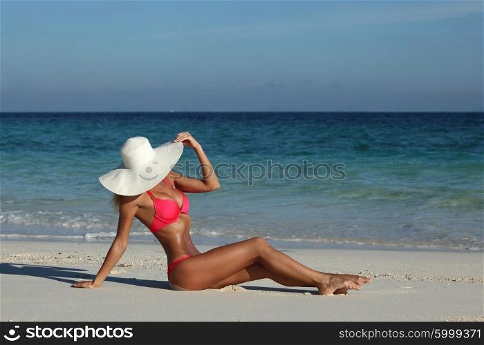 Woman sitting on the beach . Gorgeous woman sitting on the beach in sunhat