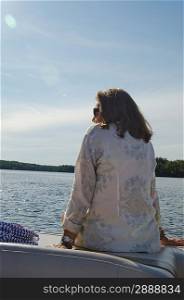 Woman sitting on the edge of a boat, Lake of the Woods, Ontario, Canada