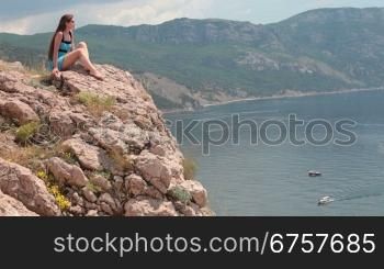 Woman sitting on the edge of a cliff Balaklava, Crimea, Ukraine