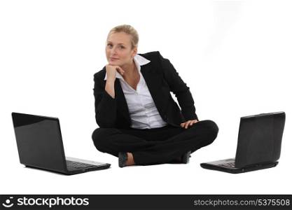 woman sitting on the floor with two laptops