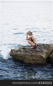 woman sitting on the rocks at the beach